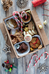 A DIY festive cookie box with homemade baked goods, on a rustic wooden table.