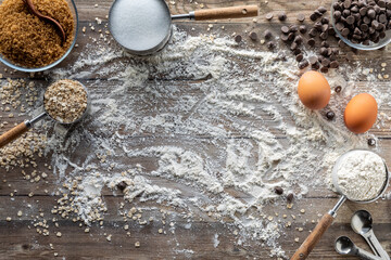 Baking ingredients scattered around on a rustic wooden table.