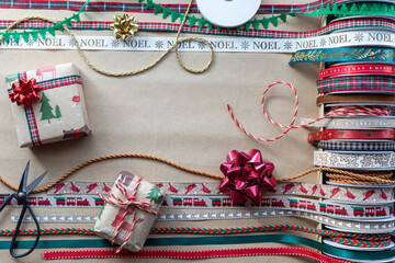 Various Christmas ribbons spread across brown paper with gifts and copy space.