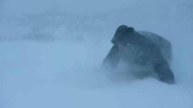 Man struggles through intense snowstorm battling harsh cold conditions in winter landscape