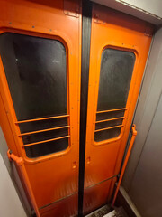 Orange metal sliding doors in a suburban electric train