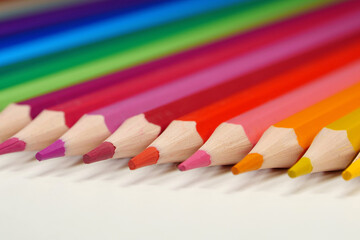 Obraz premium New wooden colored pencils of rainbow colors, perfectly sharpened, lie on table