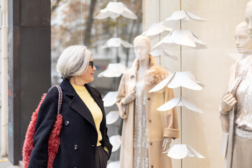 Senior woman window shopping at clothing store