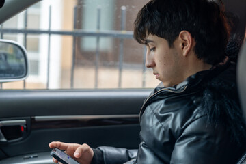 Young Man Using Smartphone in Car Passenger Seat