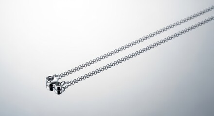 A silver necklace on a reflective surface showcasing jewelry design.