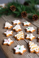 Christmas star and tree shaped cookies with white icing on a wooden table with pine branches