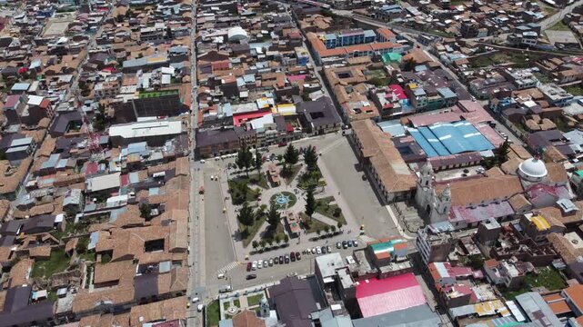 aerial panoramic view peruvian mountain town plaza, sunlit grid of terracotta roofs, central church