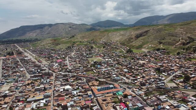 aerial peruvian mountain town panorama under moody clouds with dense rooftops and winding streets in