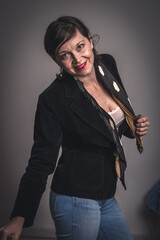 A woman in a black jacket and blue jeans is smiling and posing for a picture. Concept of confidence and happiness, as the woman is enjoying herself and is comfortable in her outfit
