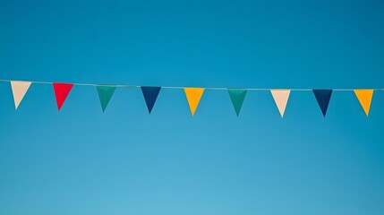 Obraz premium Festive Banner Against Azure Sky: A vibrant string of colorful triangle flags dances against a clear, azure sky, evoking a sense of festivity and joy.