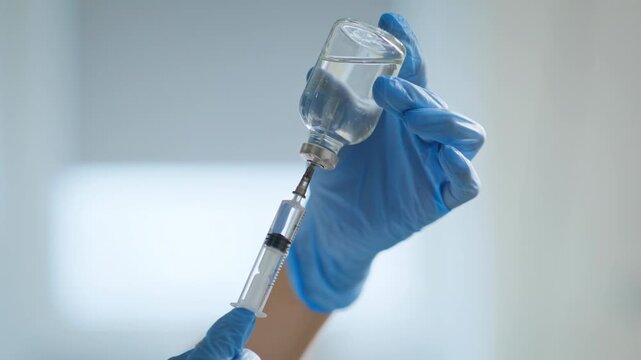Nurse hands preparing vaccine dose for injection closeup. Doctor filling syringe