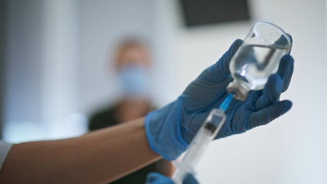 Medical nurse hands preparing vaccine injection closeup. Doctor filling syringe
