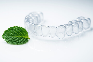Transparent Plastic Dental Aligner and Fresh Mint Leaf for Modern Orthodontics