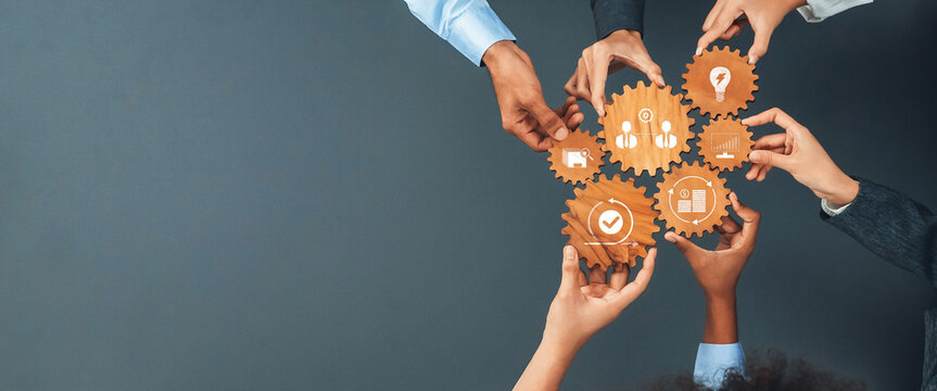 A diverse group of hands holds gears symbolizing key business concepts. This image portrays teamwork and collaboration in a professional setting, ideal for various projects. Amity