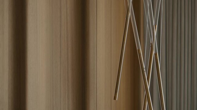 Vertical wood panels meet ribbed textures in clean contrast. Golden rods cross the foreground, adding structure and elegance. Space feels quiet, modern and refined.