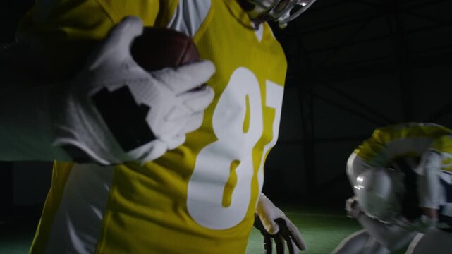 Medium slowmo shot of Caucasian male gridiron football athlete catching lateral pass from teammate being attacked by rival, then running to end zone during match at stadium