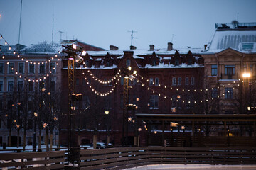 City street with Christmas decorations and glowing garlands outdoors. Winter holiday season.