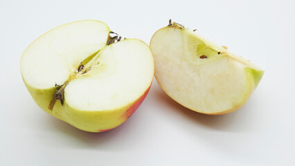 Freshly cut apple halves on a white surface showing the inside texture and color of the fruit