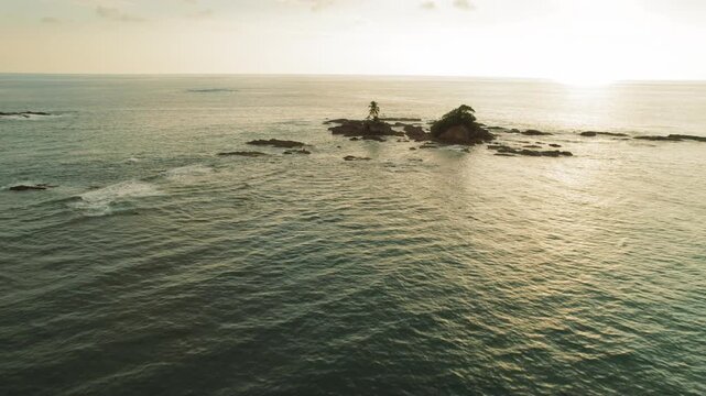 Aerial view of rocky tropical islet in turquoise ocean during golden sunset