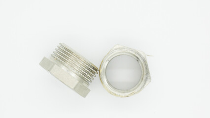 Close view of threaded metal fittings resting on a plain surface in an industrial setting during daylight