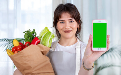 young woman holding a shopping bag full of groceries