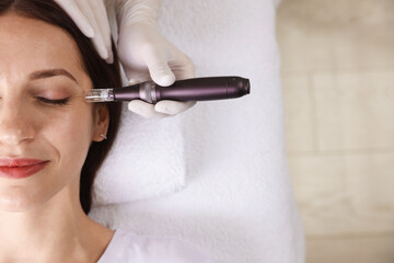 Woman undergoing microneedling procedure in beauty salon, top view. Space for text