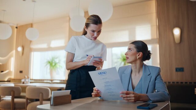 Restaurant guest talking waitress reading menu making order at cozy cafe closeup