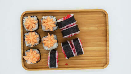 Fresh sushi rolls on a wooden tray with different toppings served in a casual dining setting at lunch time