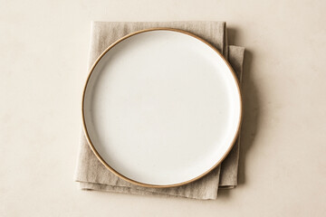 Minimalist Overhead View of White Ceramic Plate on a Beige Linen Napkin.