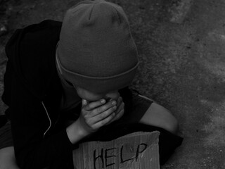 Beggar.Homeless boy or teenager begs for alms.Black and white 