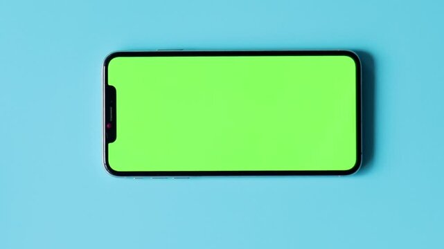 Smartphone with Green Screen on Blue Background. Concept mockup and green blank on phone for advertising on light background