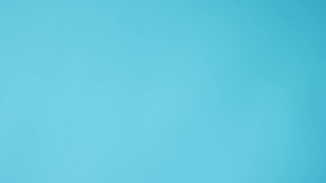 A phone with a green background lies on a bright blue background and a man's hand takes it. flatlay