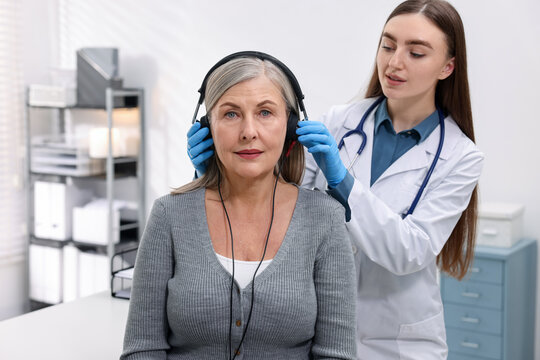 Hearing test. Doctor adjusting patient's audiometric headphones in clinic