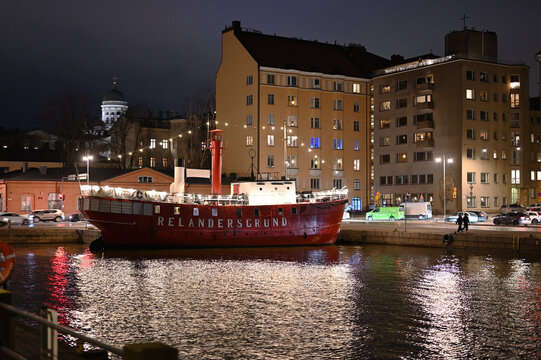 A historic red lightship lies moored along the Helsinki waterfront at night