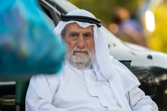 Senior arab man sitting outdoors wearing traditional arab clothing, and observing. High quality photo