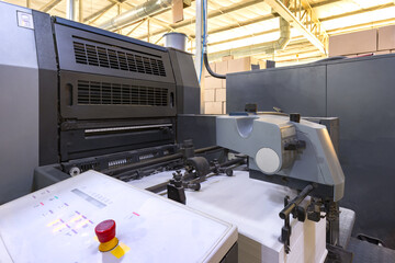 The paper loading section of a large offset printing press featuring a tall stack of white sheets ready for production.