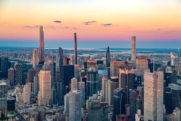 The iconic Billionaires Row skyscrapers rise above the dense Midtown Manhattan skyline during a vibrant sunset.