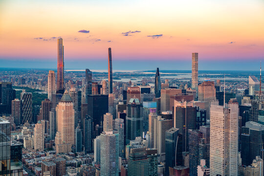 The iconic Billionaires Row skyscrapers rise above the dense Midtown Manhattan skyline during a vibrant sunset.