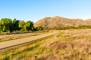 Winding Paved Path Through Grassy Field and Mountains at Lake Perris