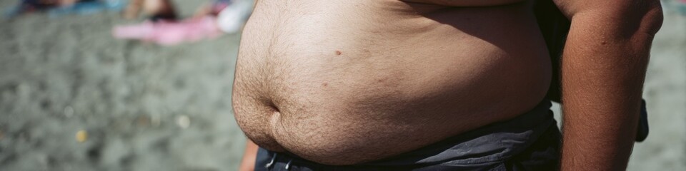 Fototapeta premium Close-up of an adult male midsection on a sandy beach