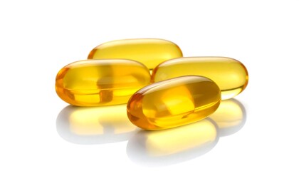 Four golden capsules gleam against a white backdrop, their translucent surfaces reflecting light softly