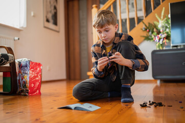 Young boy assembles the blocks looking at the instructions
