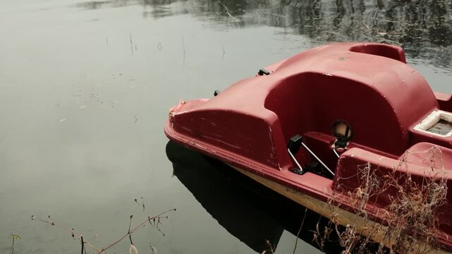 Abandoned pedal boat floating on a foggy lake with still water and soft mist. Moody outdoor scene showing neglect, silence and calm atmosphere in a quiet natural landscape. Horizontal 4k footage