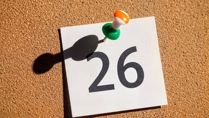 Paper sheet with printed number "26" pinned to corkboard  