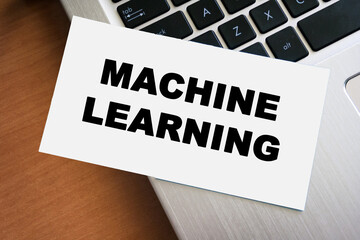 Handwritten text reading MACHINE LEARNING on a white card, placed on a laptop keyboard. This image represents technology, education, and innovation in the digital age.