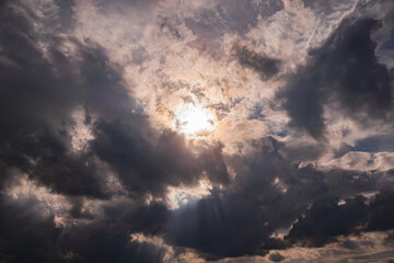 Sunlight bursts through thick clouds, creating a stunning display in the afternoon sky