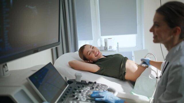 Doctor performing ultrasound pregnant patient. Professional reviewing sonogram