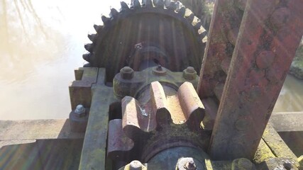 Old rusty gears of a weir on a river