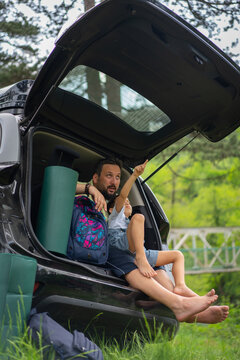 Vertical View of Man and Child Relaxing in Car Tailgate Outdoors. High quality photo
