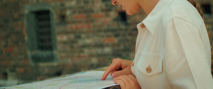 Tourist studies city map near a historic brick wall during summer trip to Milan